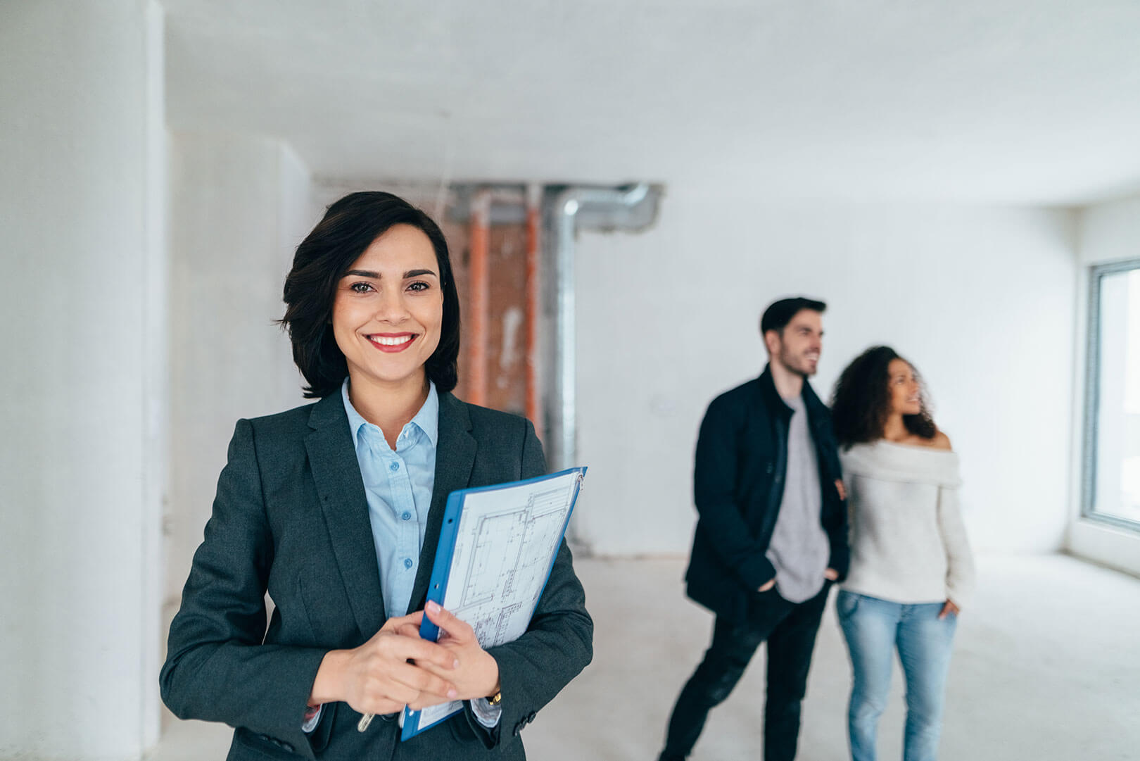Agent with a file while buyers view a property